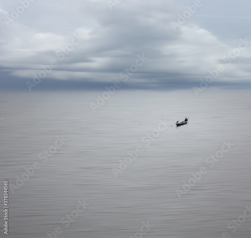 Beautifull nature with long distance of fisherman on the boat in smooth sea and clear sky,motion blur effect and minimalism.