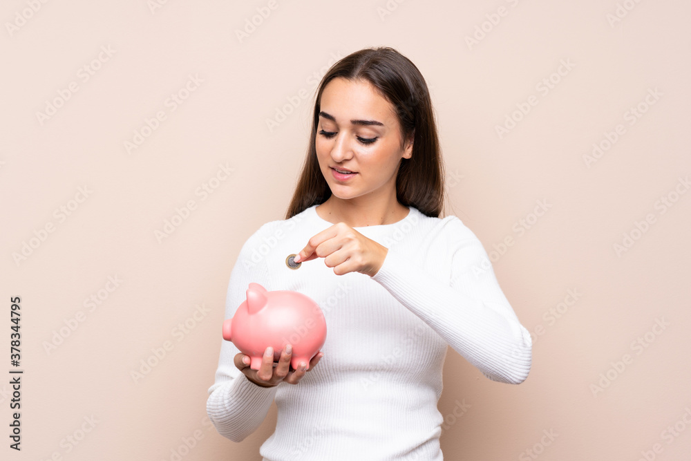 Young woman over isolated background holding a big piggybank Young woman over isolated background holding a big piggybank