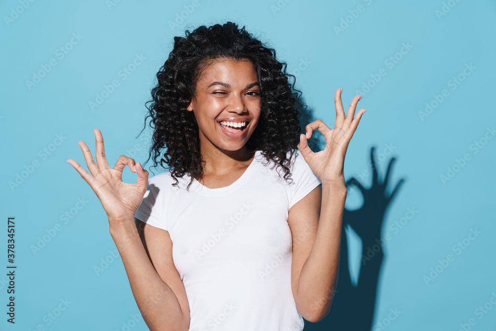 Image of happy african american girl winking and showing ok sign