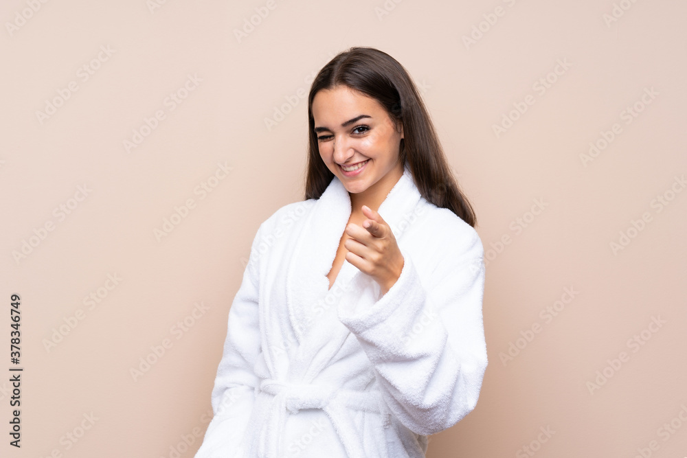Young girl in a bathrobe over isolated background points finger at you Young girl in a bathrobe over isolated background points finger at you