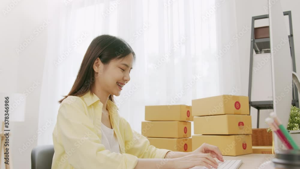 Startup small business, A young Asian woman checking online order on digital laptop and packing boxes for products to send to customers. working at the home office. Startup small business, A young Asian woman checking online order on digital laptop and packing boxes for products to send to customers. working at the home office.