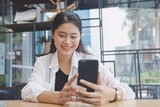 Asian woman using smart phone in coffee shop.