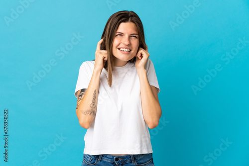 Young slovak woman isolated on blue background frustrated and covering ears