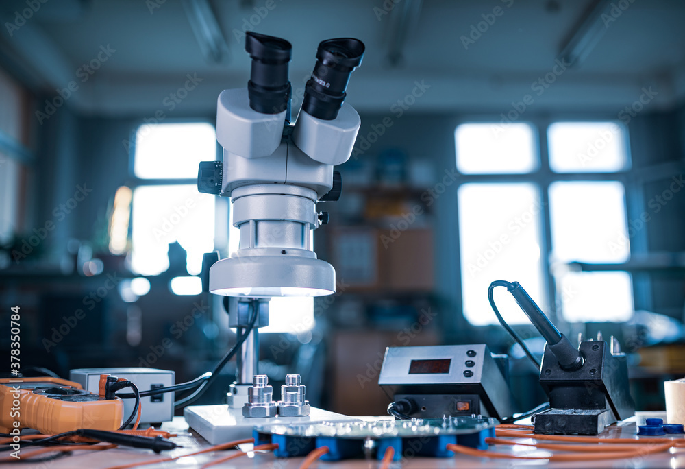Modern microscope, connectors component and large green microcircuit in workshop laboratory Modern microscope, connectors component and large green microcircuit in workshop laboratory