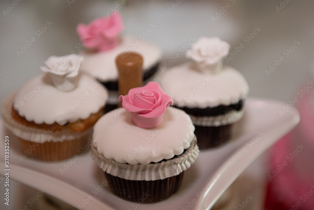 Fresh delicious cupcakes with white sugar garnish and pink sweet flower on top