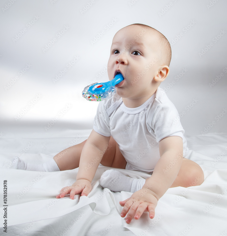 Image of a ten-month-old baby with blue rattle in mouth Image of a ten-month-old baby with blue rattle in mouth