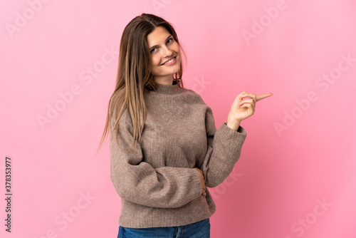 Young slovak woman isolated on pink background pointing finger to the side