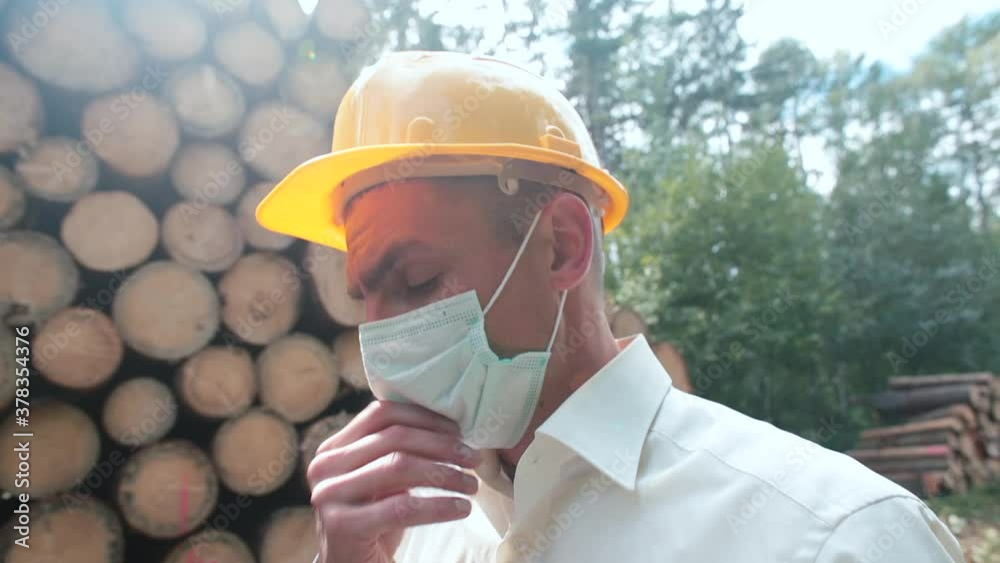A masked worker feels symptoms of a cold at a sawmill. Cough, dizziness, weakness. A breath of
