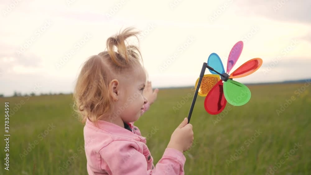 little daughter girl play pinwheel a wind toy. happy family concept