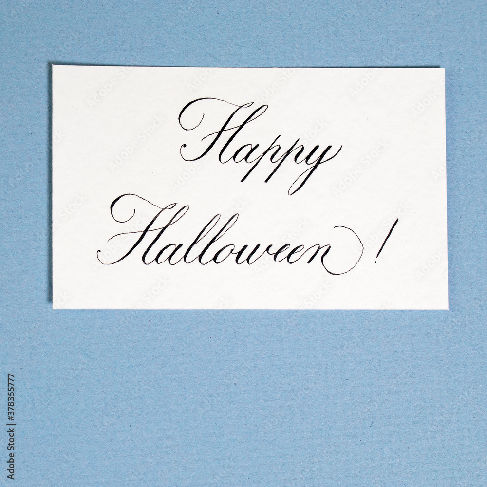 Calligraphic inscription Happy halloween on white textured paper, on blue paper card Calligraphic inscription Happy halloween on white textured paper, on blue paper card