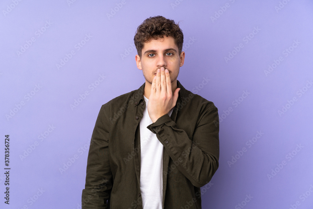 Caucasian man isolated on purple background covering mouth with hand Caucasian man isolated on purple background covering mouth with hand