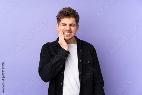 Caucasian man isolated on purple background with toothache © luismolinero