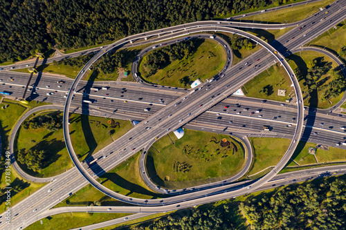 a panoramic view of the road with a complex system of interchanges with the city in the background filmed from a drone