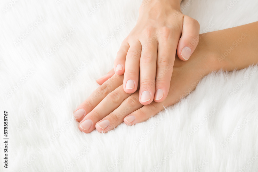 Young woman hands without nail polish on white fluffy fur blanket. Closeup. Young woman hands without nail polish on white fluffy fur blanket. Closeup.
