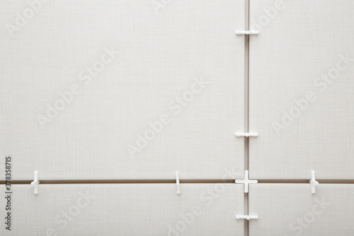 Valokuva White plastic cross in seam between gray ceramic tiles