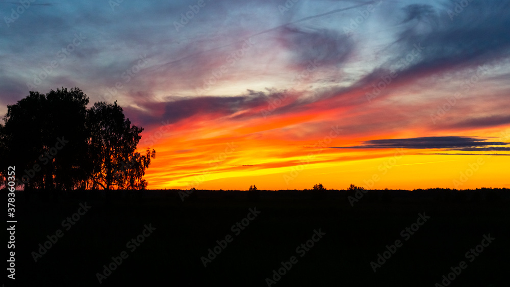 bright sunset over a field and a river in siberia