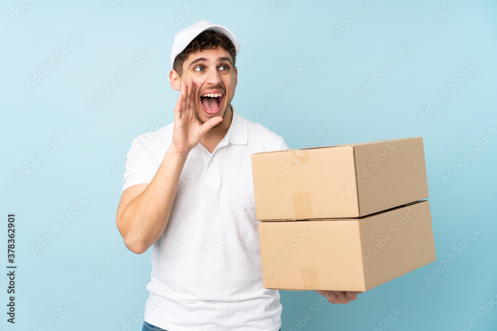 Delivery caucasian man isolated on blue background shouting with mouth wide open Delivery caucasian man isolated on blue background shouting with mouth wide open
