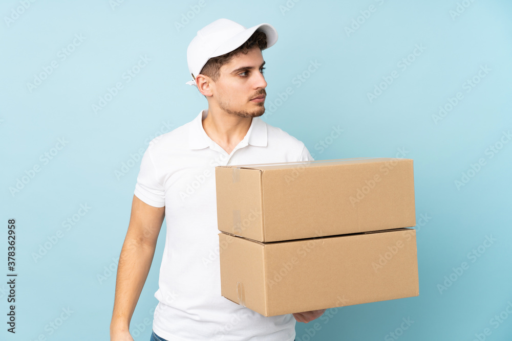 Delivery caucasian man isolated on blue background looking side