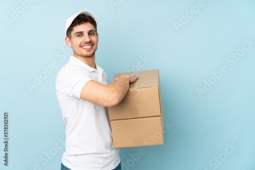 Delivery caucasian man isolated on blue background laughing