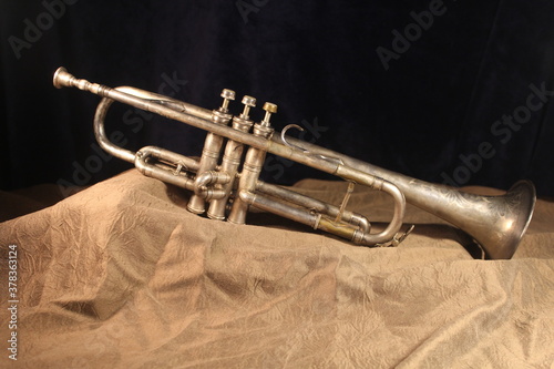 old antique brass trumpet standing on top of a brown blanket