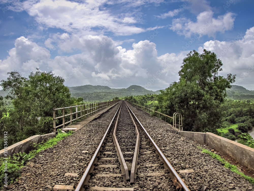 Fototapeta premium Converging rail track over bridge with nice blue sky and clouds background.