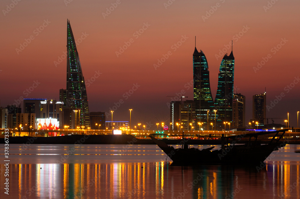 MANAMA , BAHRAIN - DECEMBER 02: Bahrain iconic towers and traditional dhow with beautiful reflection during sunset on December 02, 2019, Bahrain