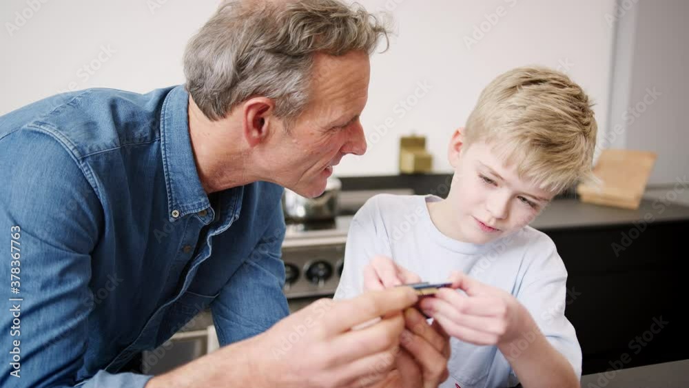 Grandson with grandfather assembling electronic components to build robot together at home - shot in slow motion Grandson with grandfather assembling electronic components to build robot together at home - shot in slow motion