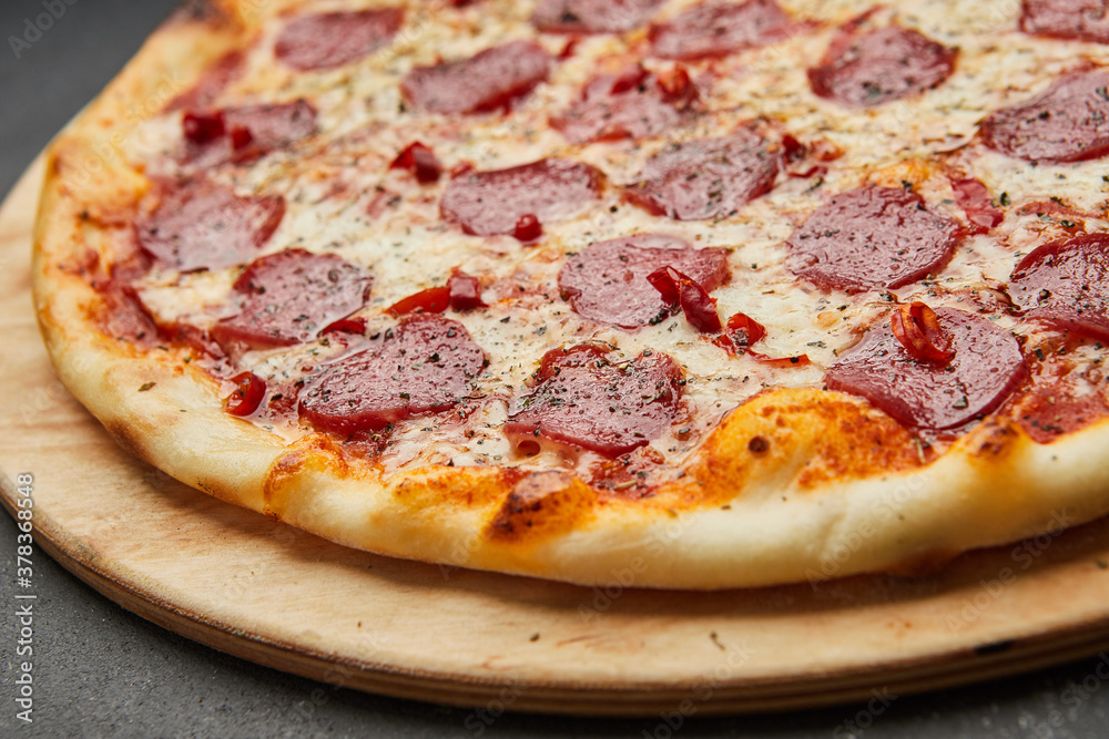 Delicious Italian Pizza pepperoni with mozzarella cheese and salami on dark background Delicious Italian Pizza pepperoni with mozzarella cheese and salami on dark background