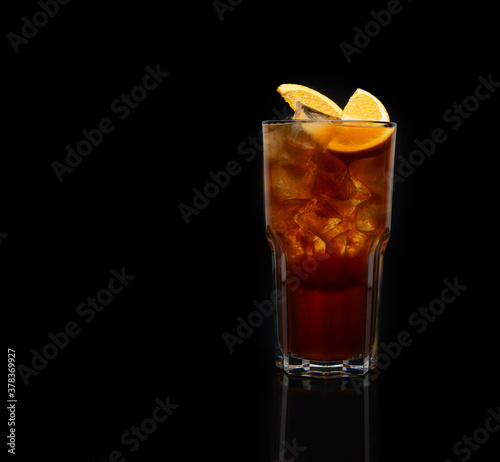 Fresh made Cuba Libre cocktail with brown rum, cola and lemon on black background