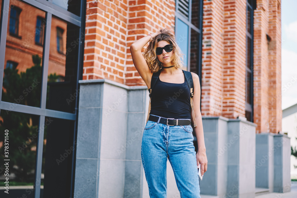Woman in denim fluffing hair while standing on street