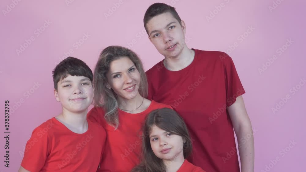 Large family of two sons and a daughter. Young beautiful mom in the middle. On a pink background. Large family of two sons and a daughter. Young beautiful mom in the middle. On a pink background.