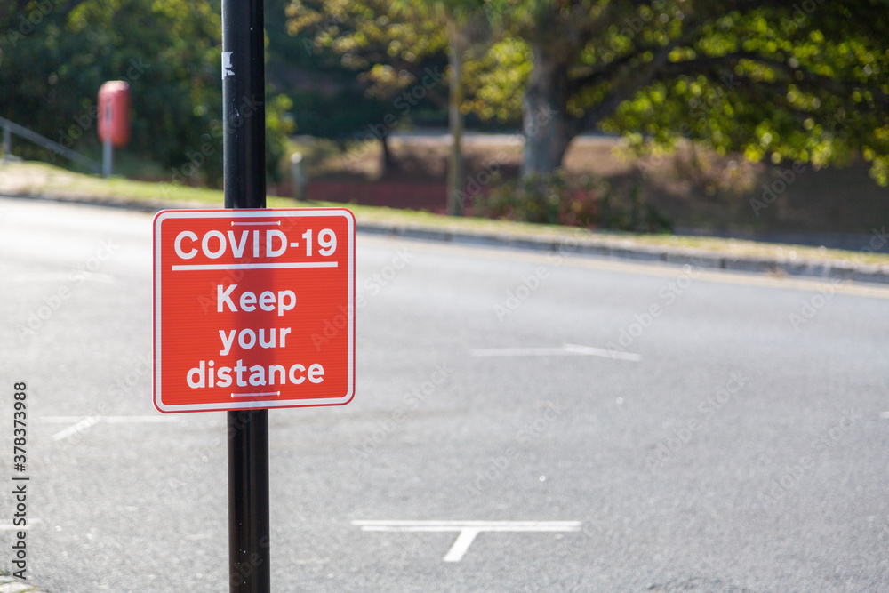 A sign reading Coviid-19 keep your distance attached to a lamppost A sign reading Coviid-19 keep your distance attached to a lamppost