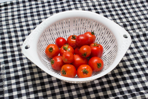 juicy red tomatoes in table cloth . caro background 