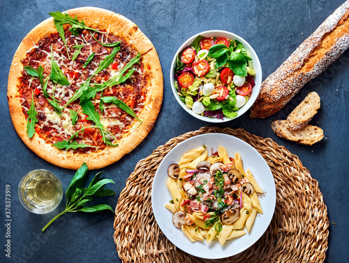 pizza with salat and pasta ready to eat on a stone undergound. photo