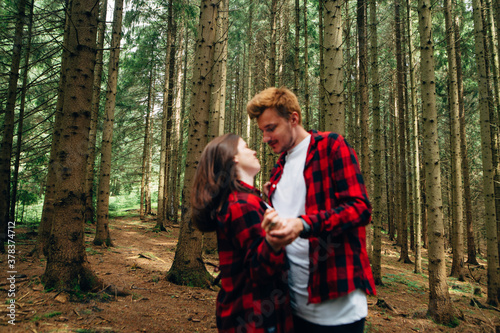 Background. Blurred, abstract photo, beautiful couple in red shirts hugging in the woods.