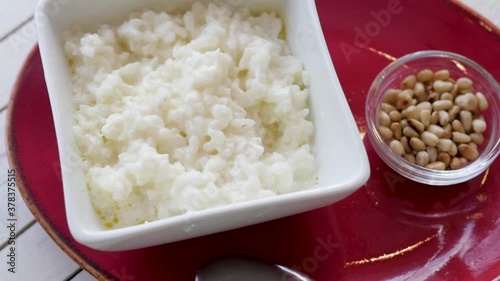 cup with rice on a white wooden background. breakfast of rice porridge. porridge in a red tarek on a white background. photo