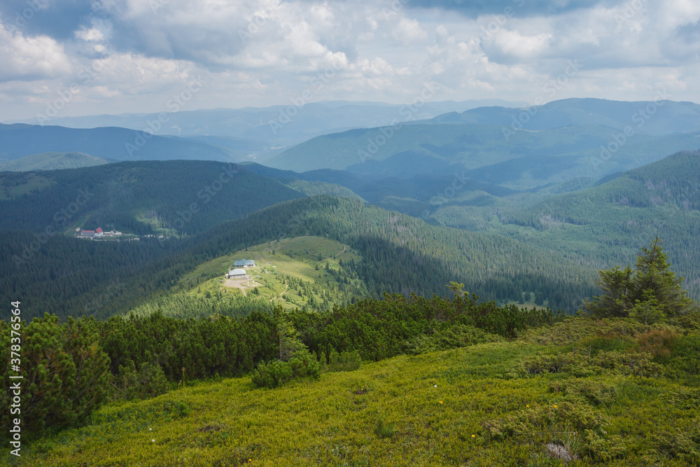 Mountain landscape. A view of the mountains with green meadows and coniferous forests against the background of beautiful clouds.   Carpathians