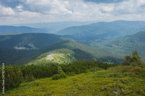 Mountain landscape. A view of the mountains with green meadows and coniferous forests against the background of beautiful clouds. Carpathians