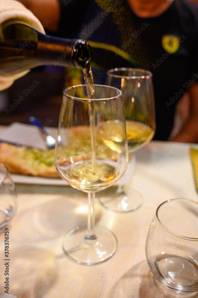 Obraz premium Pouring in glass cold dry white wine in outdoor cafe at night in Italy