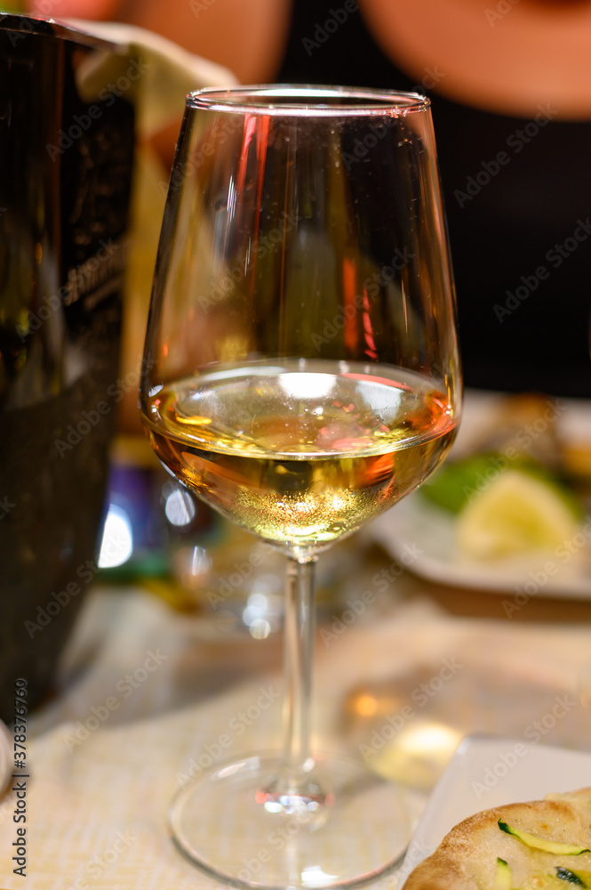 Glass of cold dry white wine served outdoor in cafe at night in Italy