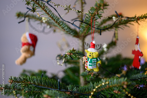 close up of a reindeer christmas decoration  hanging on a traditional real tree with lights and baubles and beads photo