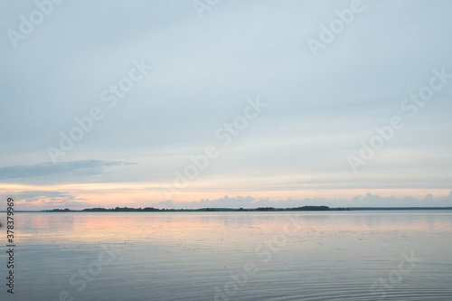 Sunset lake water horizon landscape. Sunset lake water. Sunset lake landscape. Sunset lake with cloudy sky at summer and water reflection.