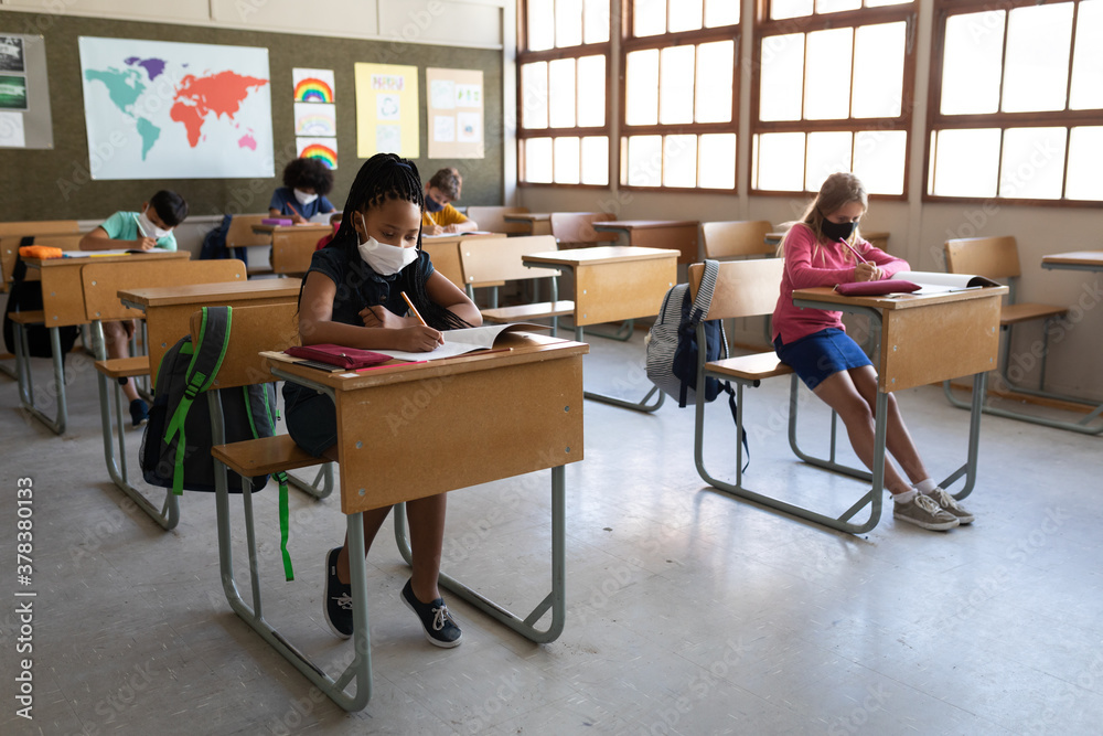Group of kids writing while sitting on their desk in class at school Group of kids writing while sitting on their desk in class at school