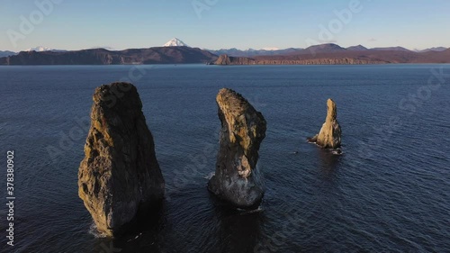 Autumn scenery, beautiful sunrise over Avacha Bay on Russia's Kamchatka Peninsula, and the famous Three Brothers Rock. The waters of the Pacific Ocean. In the background is the Avachinsky volcano.