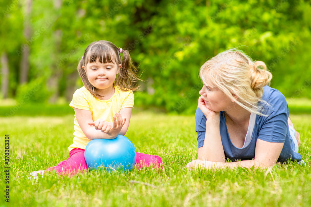 Mother talks with little girl with syndrome down in a summer park Mother talks with little girl with syndrome down in a summer park