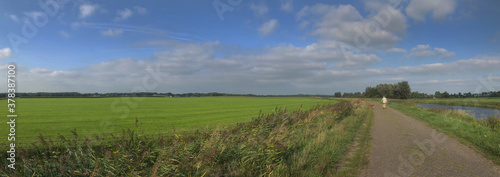Dutch polder landscapes. Havelte. Oude Vaart. Clouds. Blue sky. Drenthe Netherlands Panorama. Road. Walking the dog.