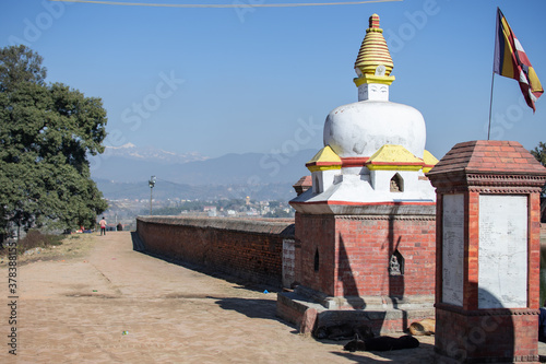 View over a stone wall with a hiindu structure and a flag attatched to it photo