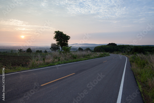 Curve of long road across through mountain view under cloudy sky