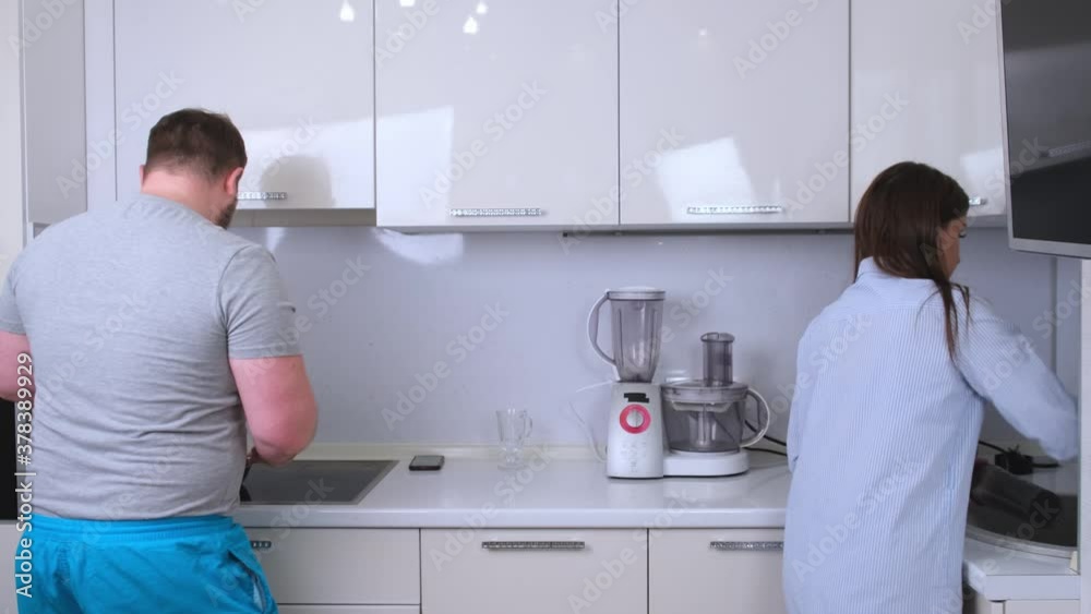 Chubby man and woman dancing and singing in the kitchen while cooking at home, the concept of a happy fun family Chubby man and woman dancing and singing in the kitchen while cooking at home, the concept of a happy fun family