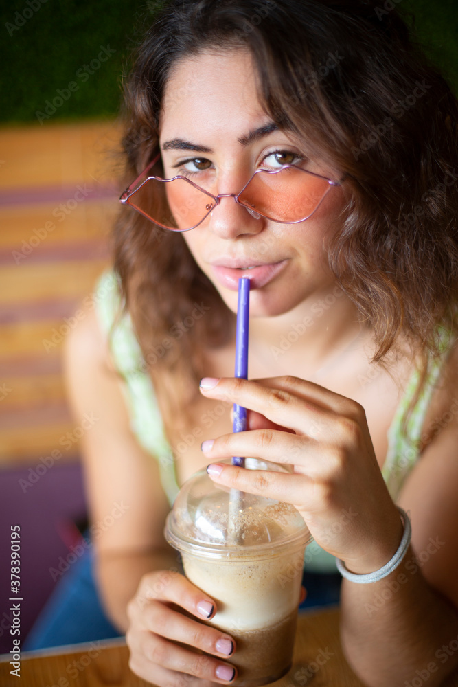 Young girl looking at camera while drinking a smoothie.